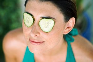 Femme qui a des rondelles de concombre sur les yeux