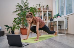Jeune femme effectuant des mouvements de sport devant son ordinateur