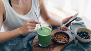 Femme qui mange des amandes avec des smoothies